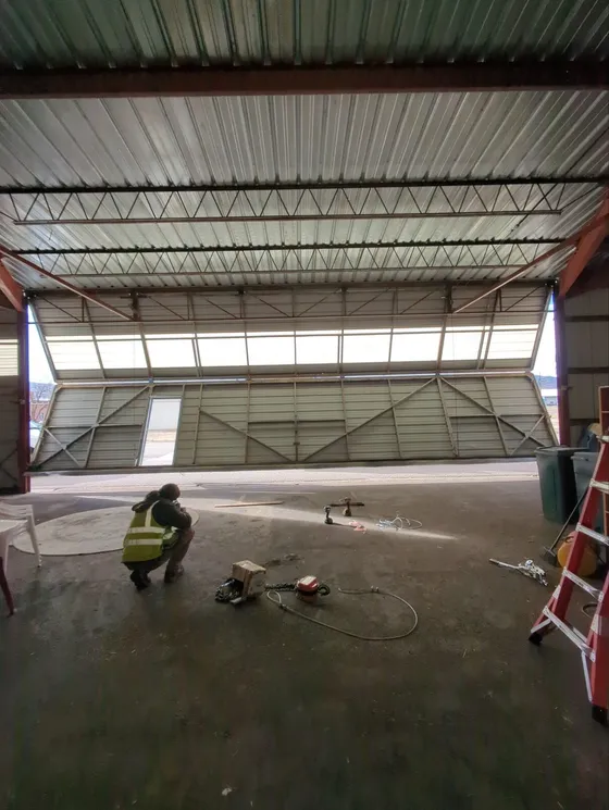 Technician servicing a bifold hangar door cable system